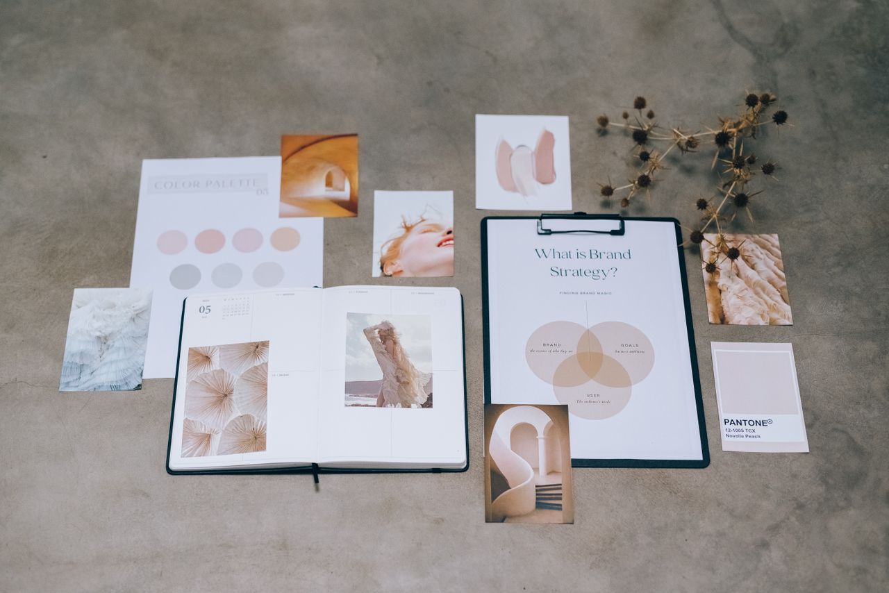 Una composizione flat lay di elementi di branding con palette colori e documenti di pianificazione strategica su una superficie in cemento.